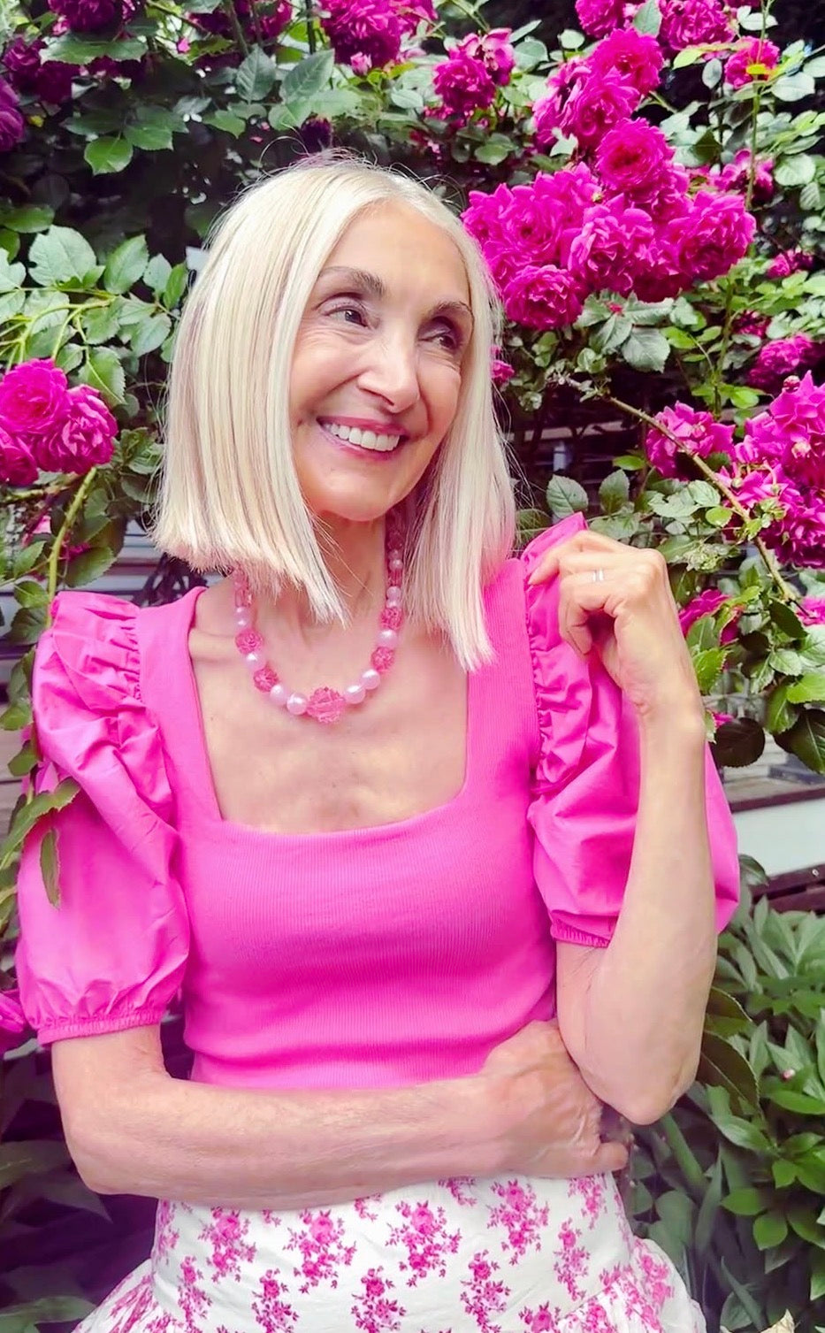 Woman in a pink outfit standing among pink flowers